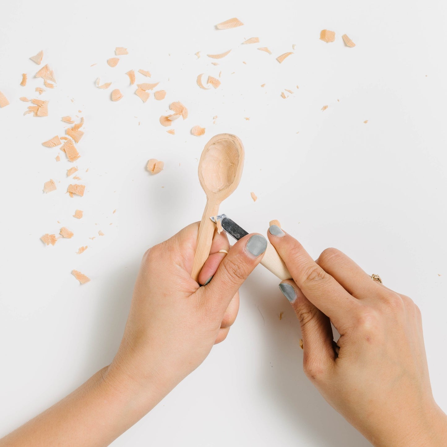 Beginner kit spoon being carved at the handle. Wood shavings shown due to the carving.
