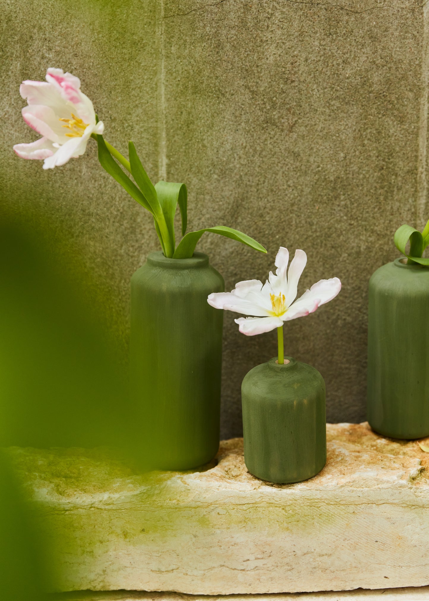 All three vases shown in the background with flowers on a rugged ledge.