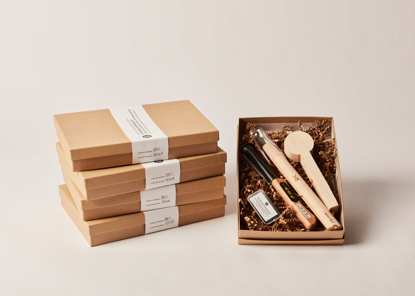 5 Orignal Spoon Carving Kits!!! By Melanie Abrantes Designs. Four stacked, closed boxes and one opened displaying wood butter, carving knife, spoon gouge, and spoon blank.