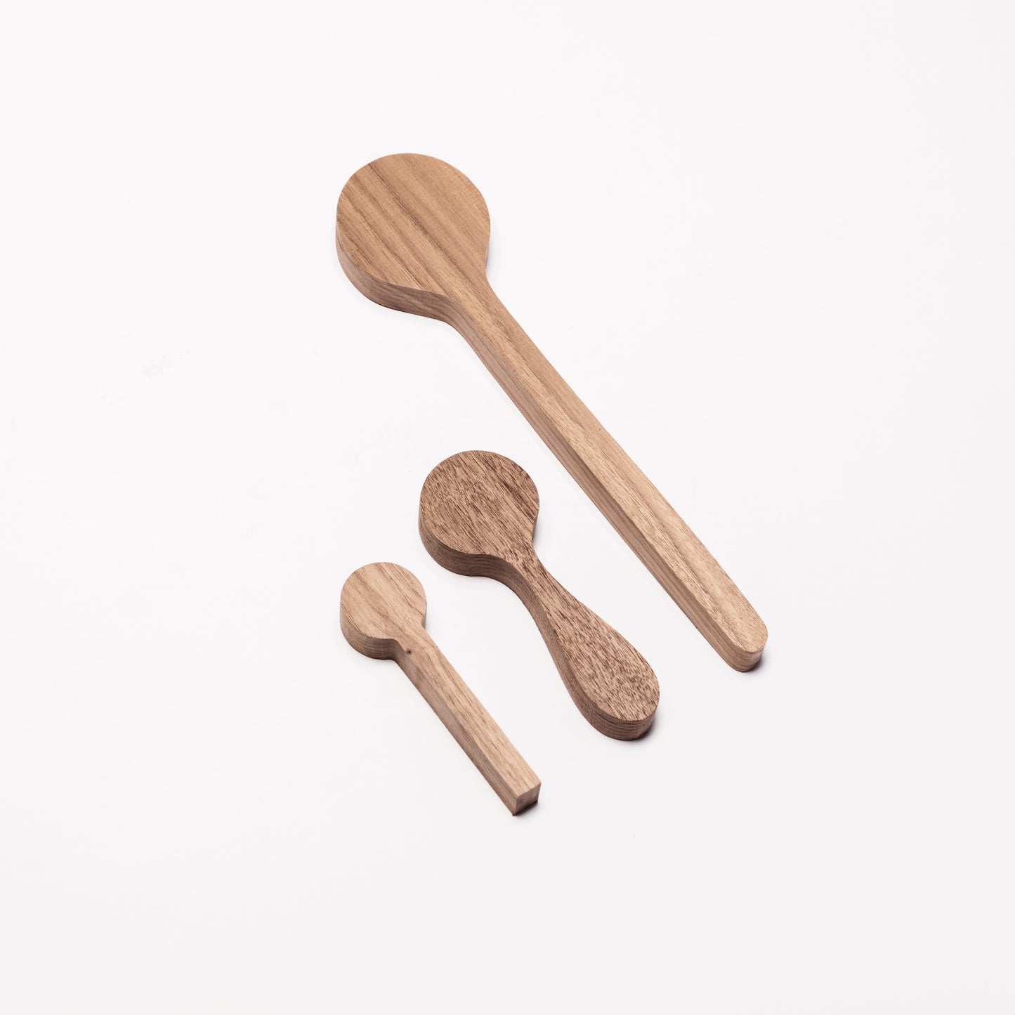 Regular, coffee, and cooking spoons in Walnut wood. At an angle. By Melanie Abrantes Designs.