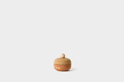 Small cork bolo canister with a pink marble cork bottom and natural cork top. The circular handle is made of maple.