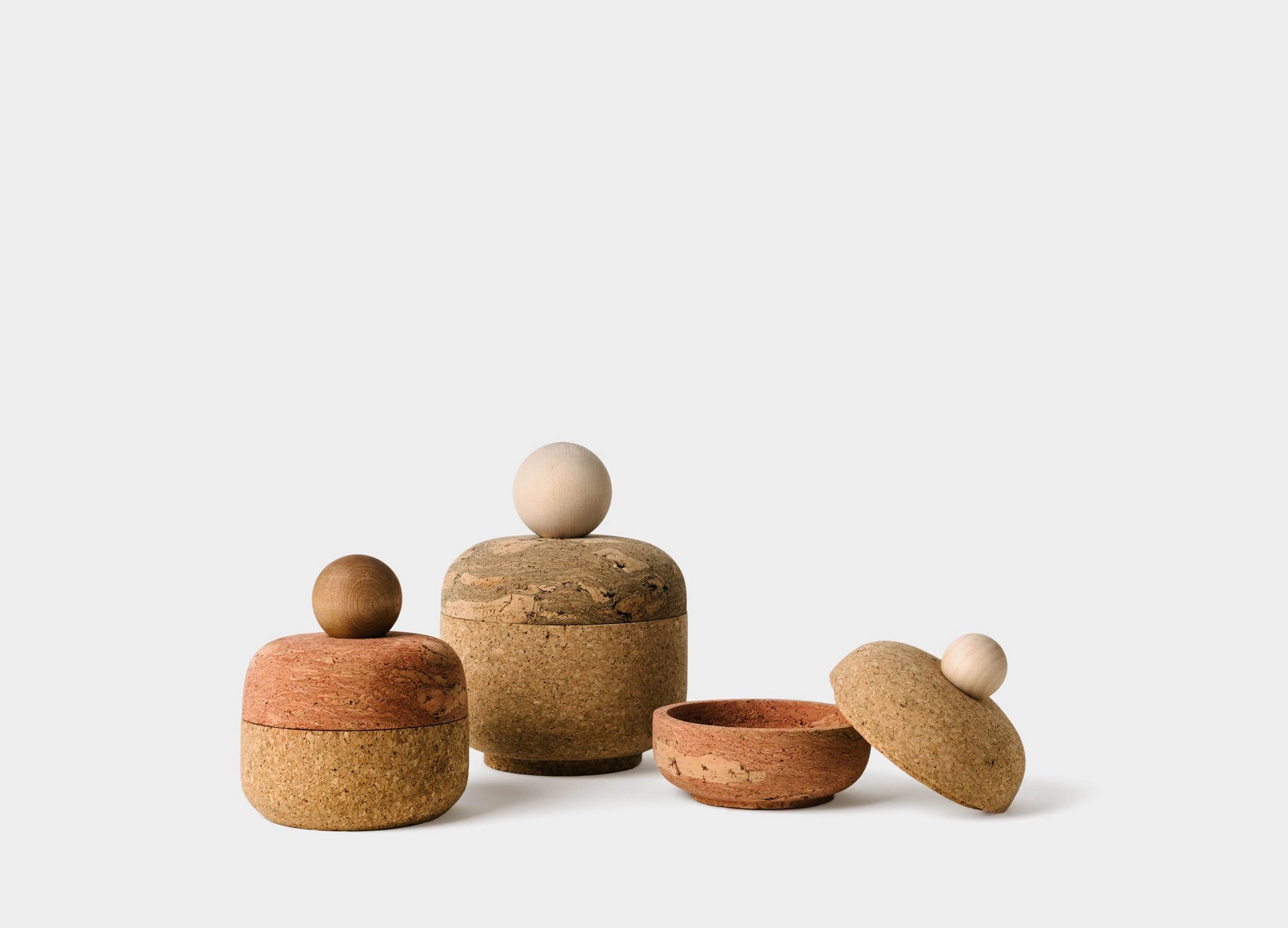Cork bolo canisters in large, medium, and small. Made of natural cork, and pink and black marble cork. Rounded edge containers with a maple round handle.