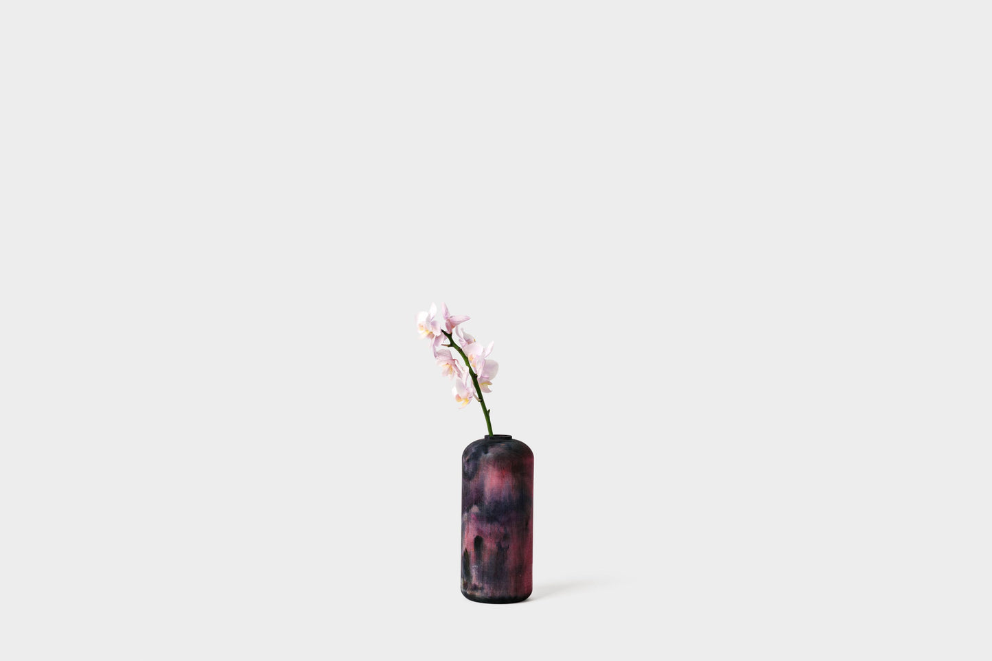 Tall vase hand-dyed in midnight with flowers inside. By Melanie Abrantes Designs.