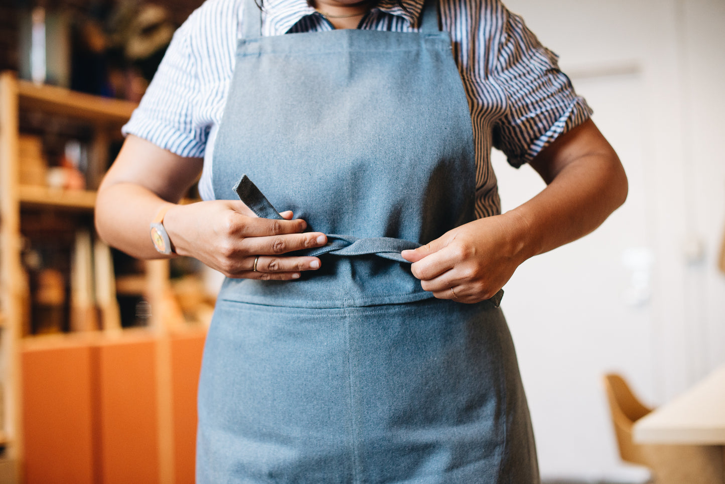 GDS studio apron collaboration shown on a model. Tying the apron in the front.