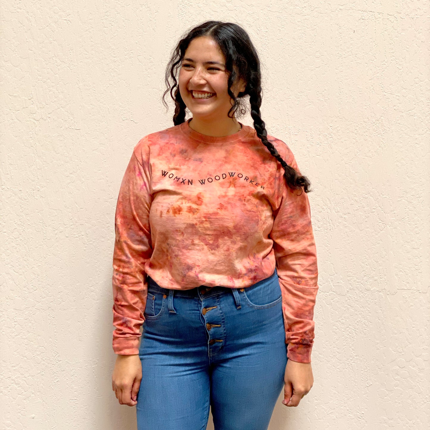 Woman with brown hair wearing tie-dye crimson and orange sweatshirt. Reads "Womxn Woodworker" in black font.