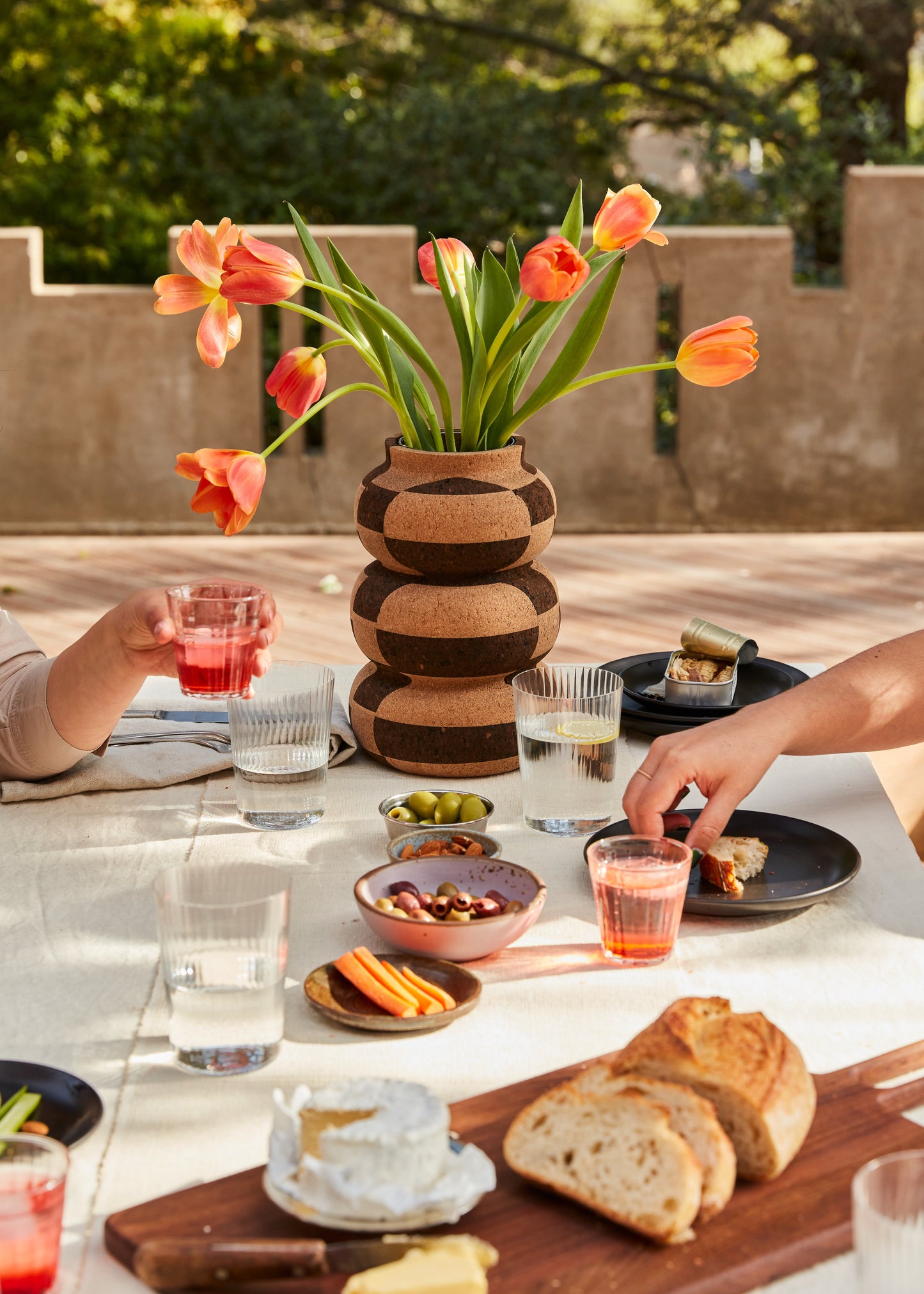 Large checkered cork vase shown on elegant white linen table setting with walnut cutting board. By Melanie Abrantes Designs.