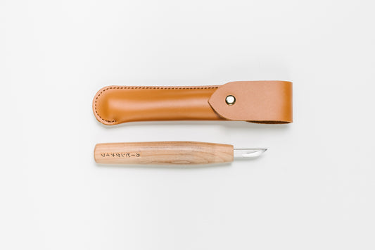 Japanese carving knife shown below its leather case.  The knife has a double beveled blade. Curated by Melanie Abrantes Designs.