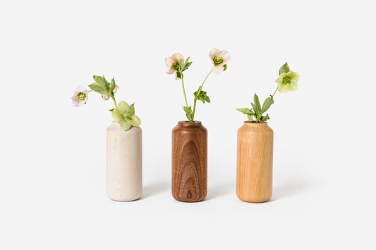 Three tall and wide wooden vases holding flowers. From left to right: Maple, Walnut, Cherry.