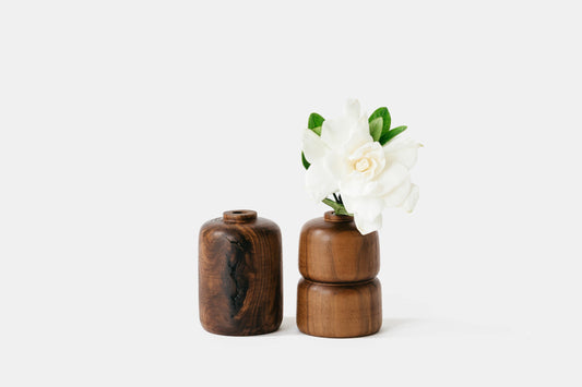 Two walnut wood bud vases holding a white flower. By Melanie Abrantes Designs.