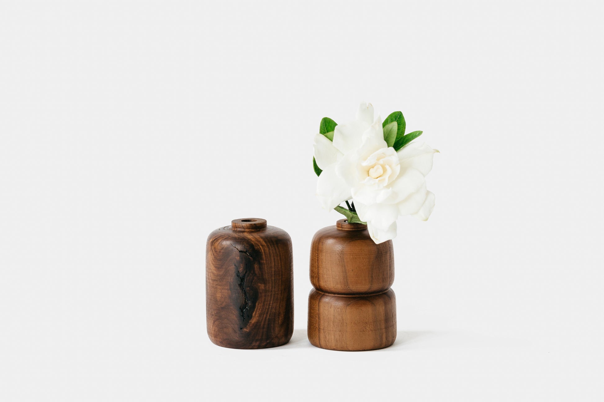 Two walnut bud vases, one holding a flower. By Melanie Abrantes Designs.