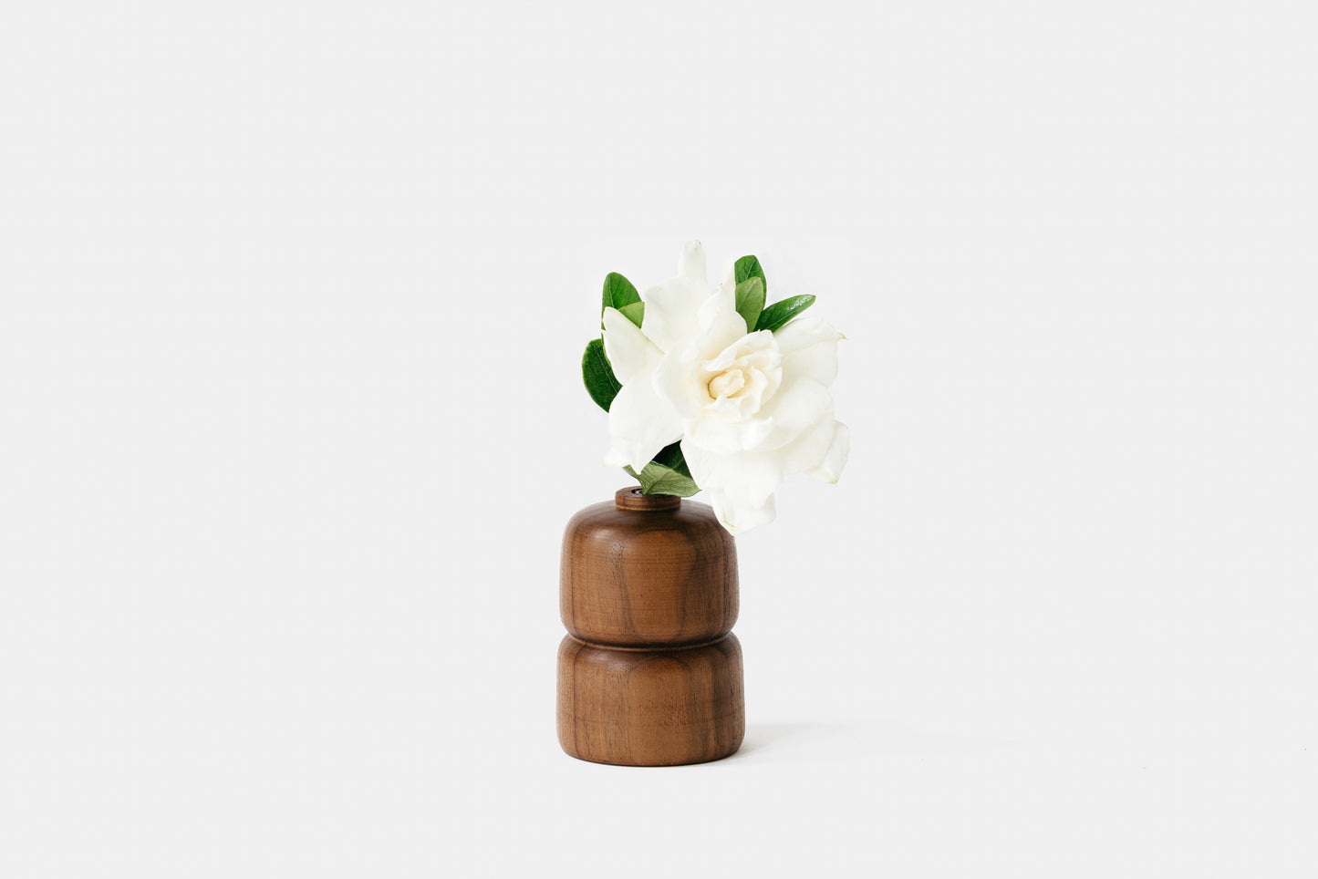 Grooved walnut bud vase holding white rose. By Melanie Abrantes Designs