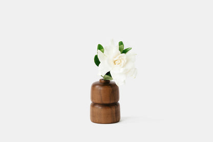 Grooved walnut bud vase holding white rose. By Melanie Abrantes Designs