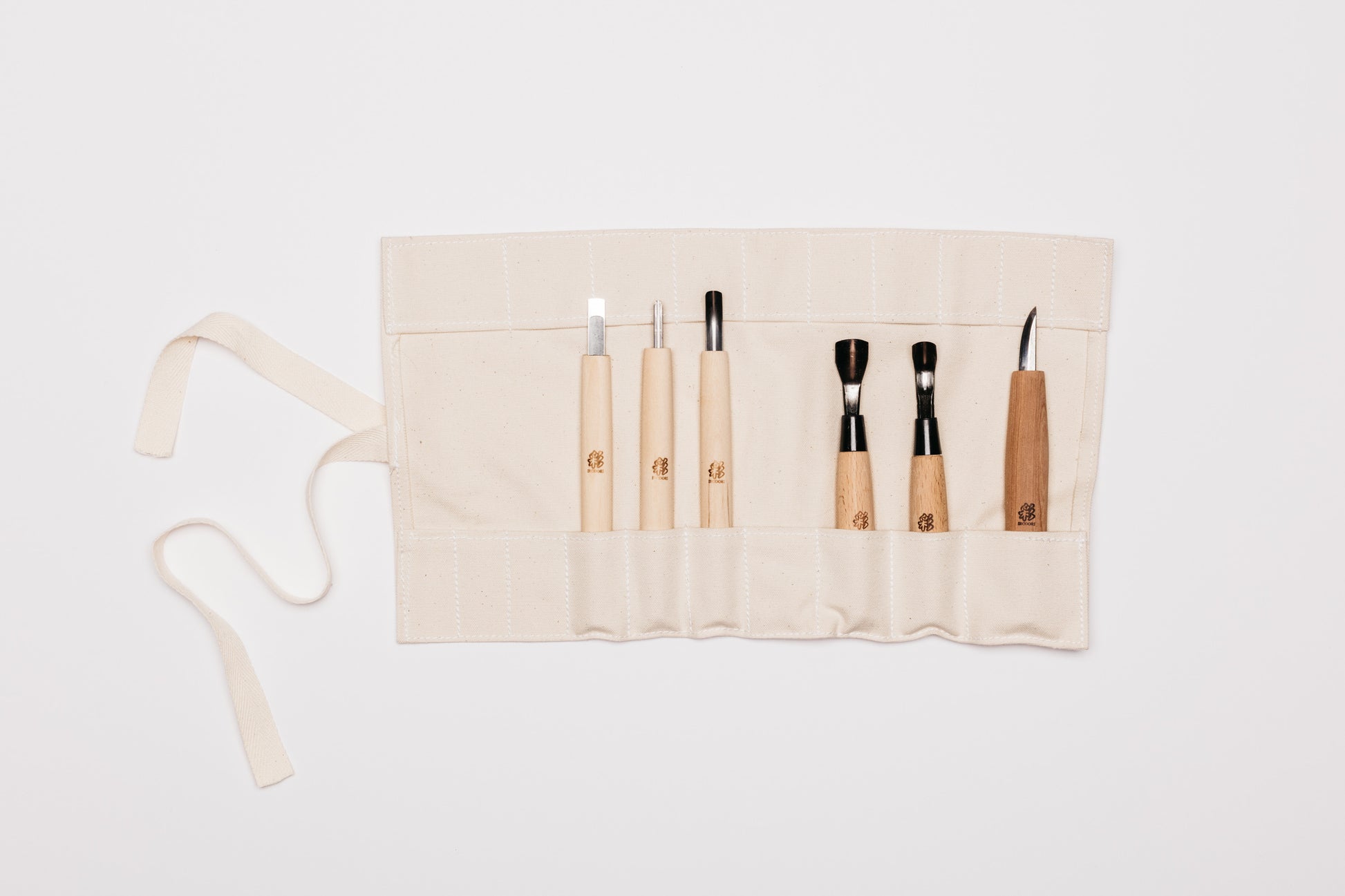 Beige tool roll laid out with all six carving tools in their individual pockets.