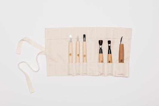 Beige tool roll laid out with all six carving tools in their individual pockets.