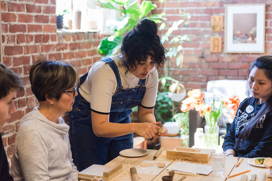 Melanie Abrantes instructing how to hold and make cuts on the spoon blank in the studio.